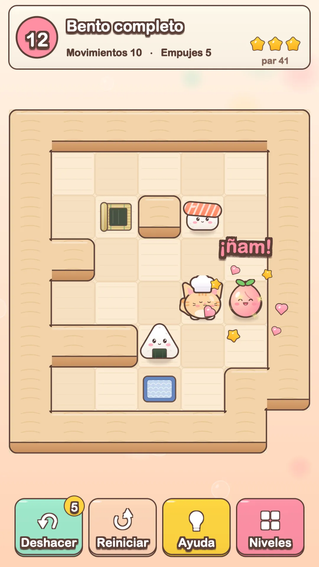 Un nivel de Neko Bento: el gatito chef empuja un onigiri, un sushi y un durazno hasta su lugar en una mesa de madera.